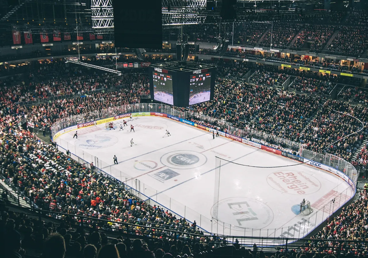 Una vista ampia di un'arena di ghiaccio durante una partita di hockey con una grande folla.