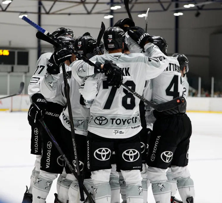 Giocatori di hockey su ghiaccio con maglie bianche con numeri neri e il logo Toyota festeggiano sul ghiaccio.