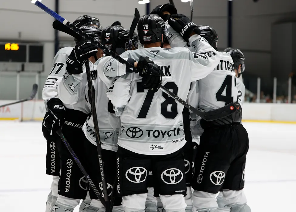 Giocatori di hockey su ghiaccio con maglie bianche con dettagli neri e il logo Toyota festeggiano sul ghiaccio.