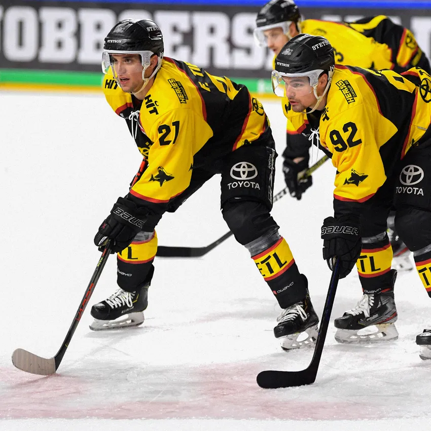 Due giocatori di hockey su ghiaccio in maglie gialle e nere sono sul ghiaccio.