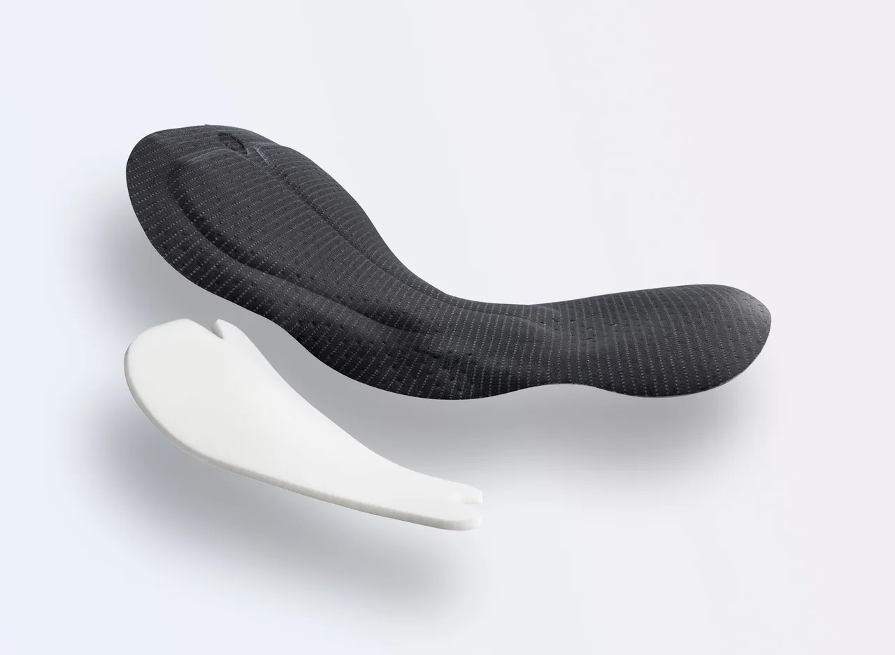 Due cuscinetti sportivi di diversi colori, uno in nero con un design testurizzato e l'altro in bianco con una forma semplice.