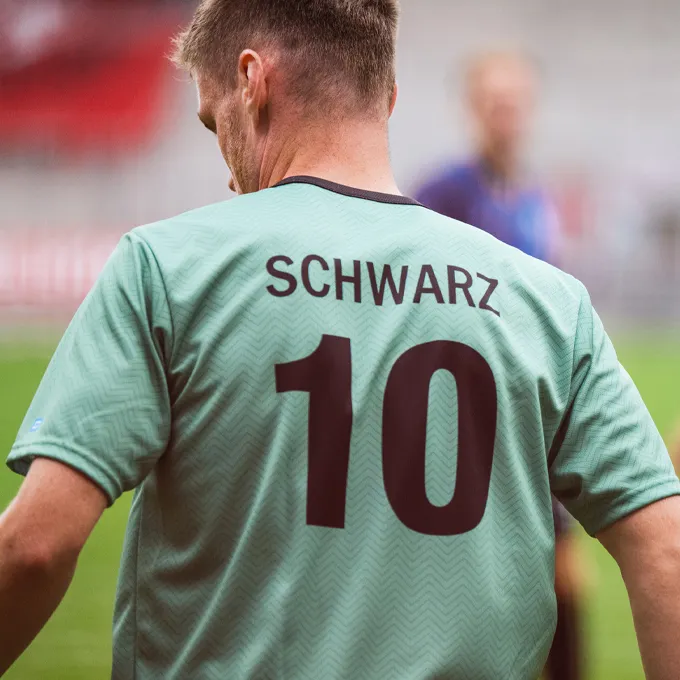 Un giocatore indossa una maglietta da calcio verde menta con il numero 10 e il nome 'SCHWARZ' sulla schiena.