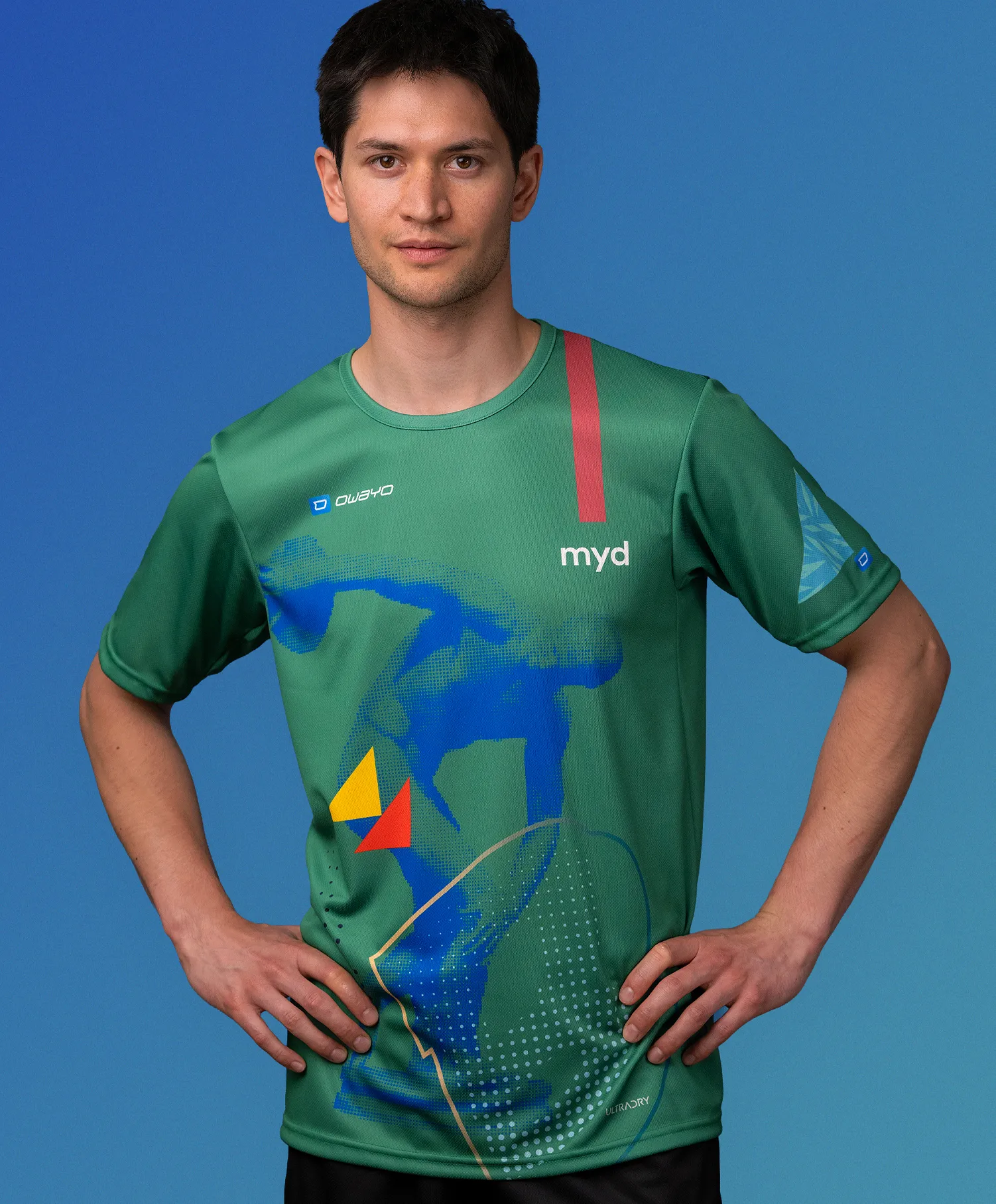 Un uomo indossa una maglia sportiva verde personalizzata di owayo con un design grafico blu, giallo e rosso e la scritta 'myd' sul petto.