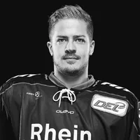 Un uomo con una maglia da hockey su ghiaccio nera con il logo owayo sul petto e la scritta 'Rhein' sul davanti.