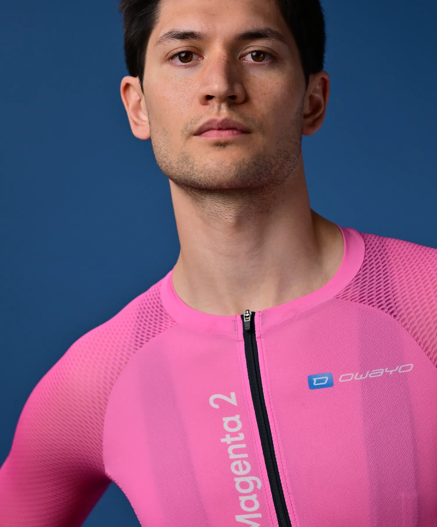 Un uomo indossa una maglia sportiva rosa senza maniche con cerniera e il logo 'owayo' sul petto.