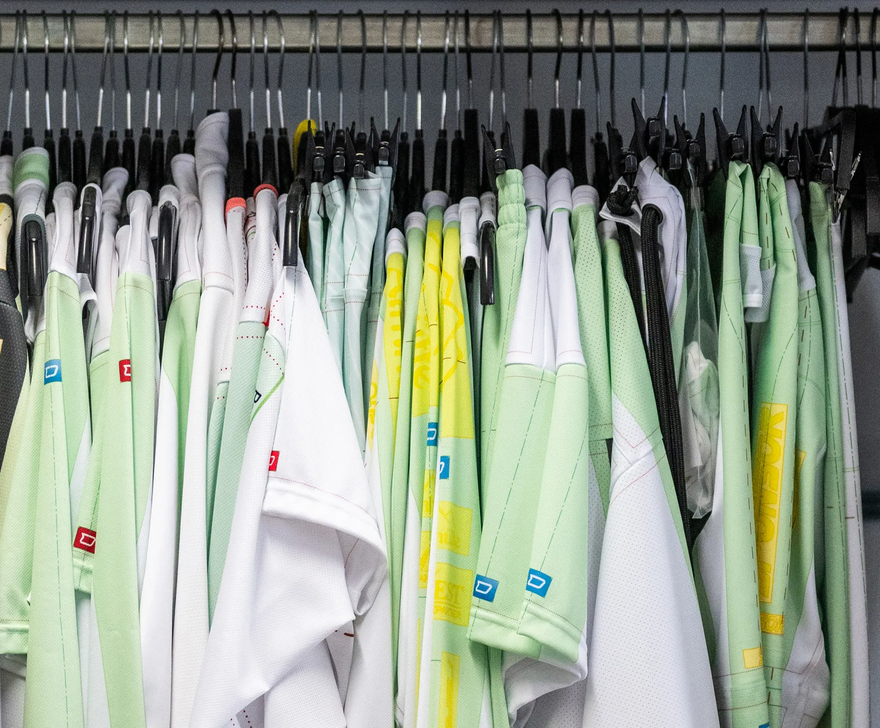 Una selezione di abbigliamento sportivo su misura in vari colori appesi a grucce.