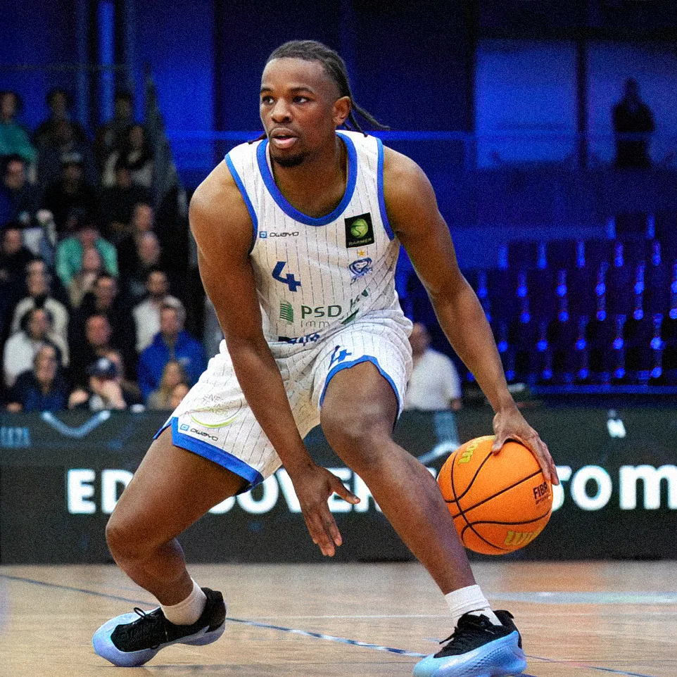 Un giocatore di basket dribbla la palla sul campo mentre indossa una maglia a righe con il numero 4.