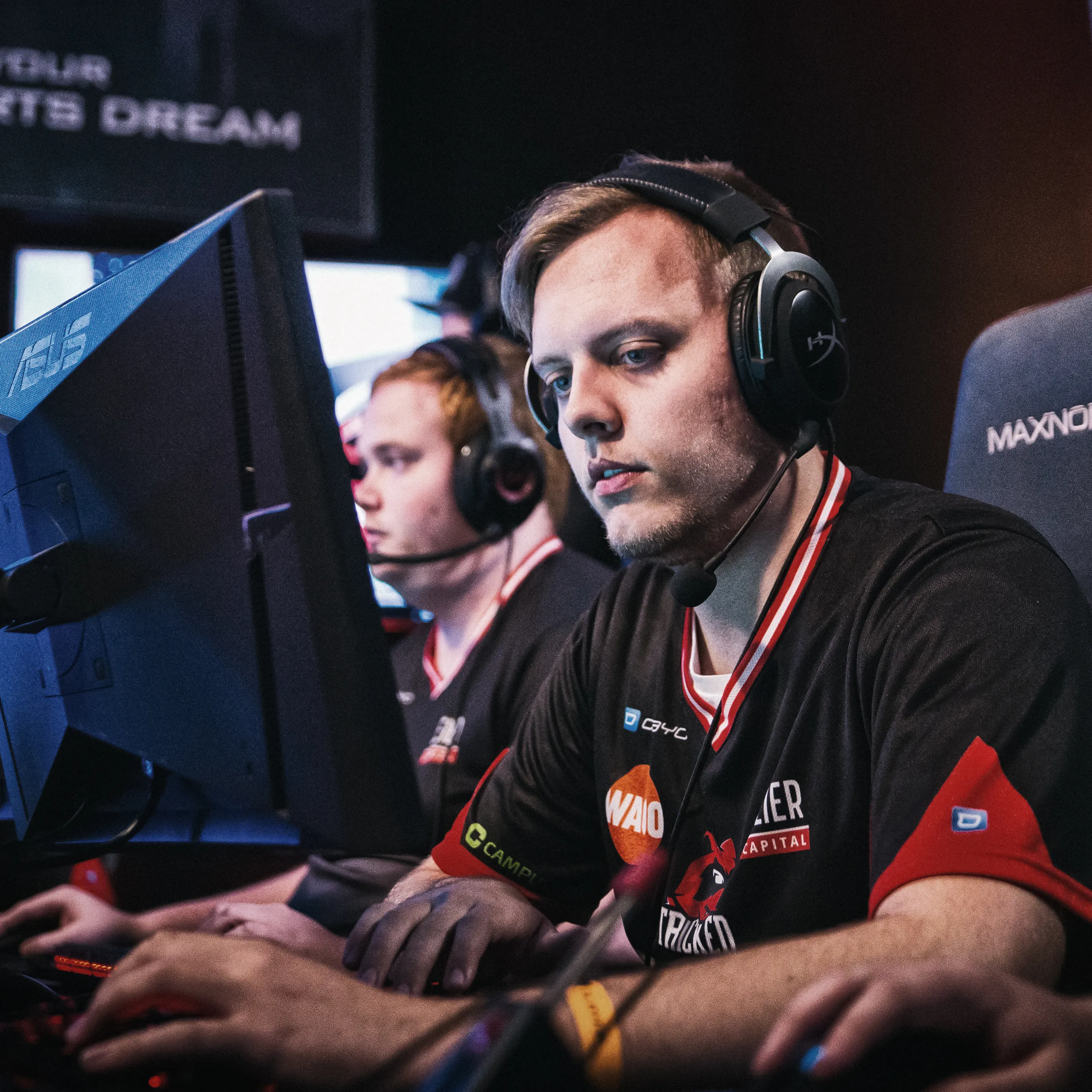 Due giocatori in magliette sportive con cuffie, concentrati sui loro computer durante un torneo di eSports.